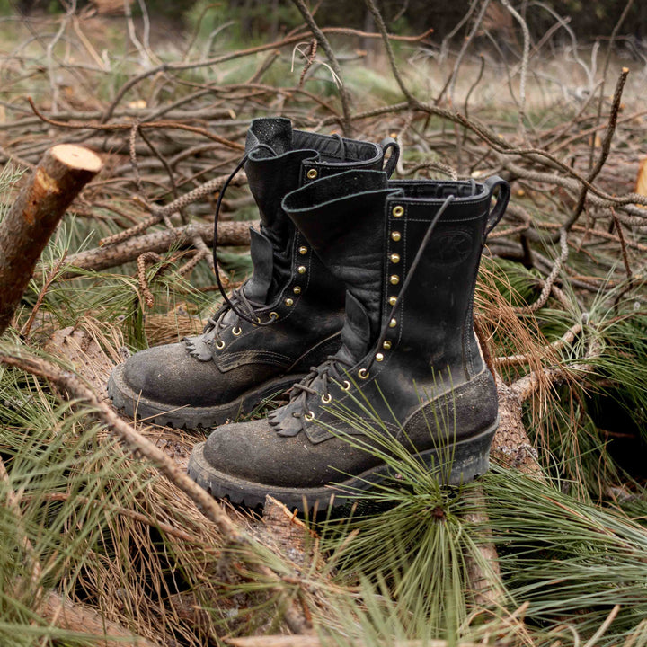 Pair of Fire Inlander black work boots on top of pine tree branches